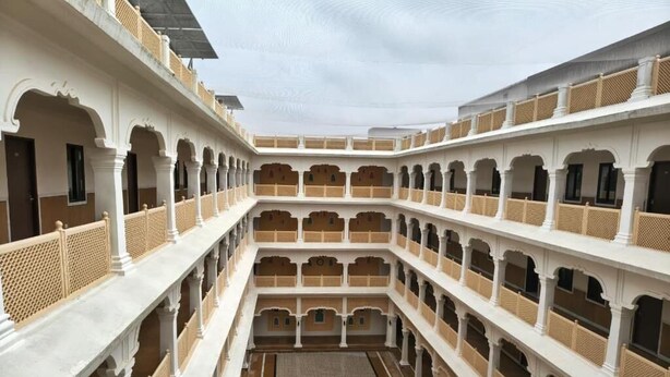 A multi-level courtyard with white and beige walls, multiple balconies, and a central open space. - Abhushan Mahal (Degana)