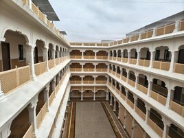 Un patio de varios niveles con paredes blancas y beige, múltiples balcones y un espacio central abierto.
