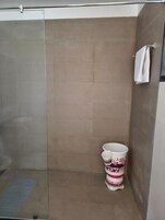 Un baño con cabina de ducha de vidrio, un inodoro con estampado floral y un perchero para toallas.