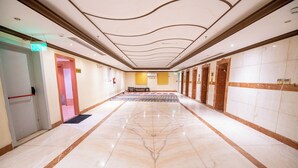 A hotel corridor with marble flooring, a patterned carpet, and a fire extinguisher on the wall. - Al Olayan Golden Hotel Misfalah (Makkah)