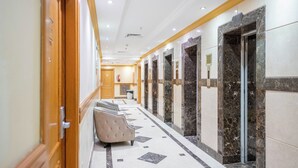A hotel corridor with marble flooring, a reception desk, and a seating area. - Al Olayan Golden Hotel Misfalah (Makkah)