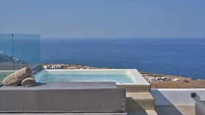 A pool with a clear view of the sea, a lounge area with a cushion, and a glass barrier. - Superior Windmill with a private jacuzzi (FC2M+X3 Imerovigli, Greece)
