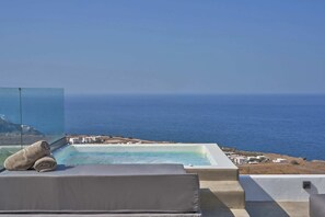 A pool with a clear view of the sea, a lounge area with a cushion, and a glass barrier. - Superior Windmill with a private jacuzzi (FC2M+X3 Imerovigli, Greece)