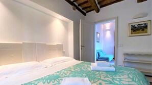 A hotel room with a large bed, a headboard, and a door leading to a bathroom. - CAMPOREGIO 31 - in the center with a view of the Duomo (Siena)