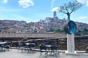 A terrace with outdoor seating and a view of historic buildings in the background. - CAMPOREGIO 31 - in the center with a view of the Duomo (Siena)