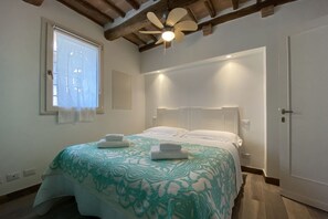 A bedroom with a bed, a ceiling fan, a window with blinds, and a door. - CAMPOREGIO 31 - in the center with a view of the Duomo (Siena)