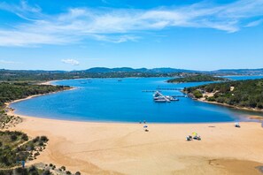 A coastal beach with boats, clear blue water, and a sandy shore. - Three-Room Suite: 70 sq m (maximum 6 guests + 1 infant in a cot - 0-2 years old), consisting of a living room with a double sofa bed, a double bedroom and a bedroom with twin beds, a bathroom with shower, and a kitchenette.Some three-room apartments have (Costa Serena)