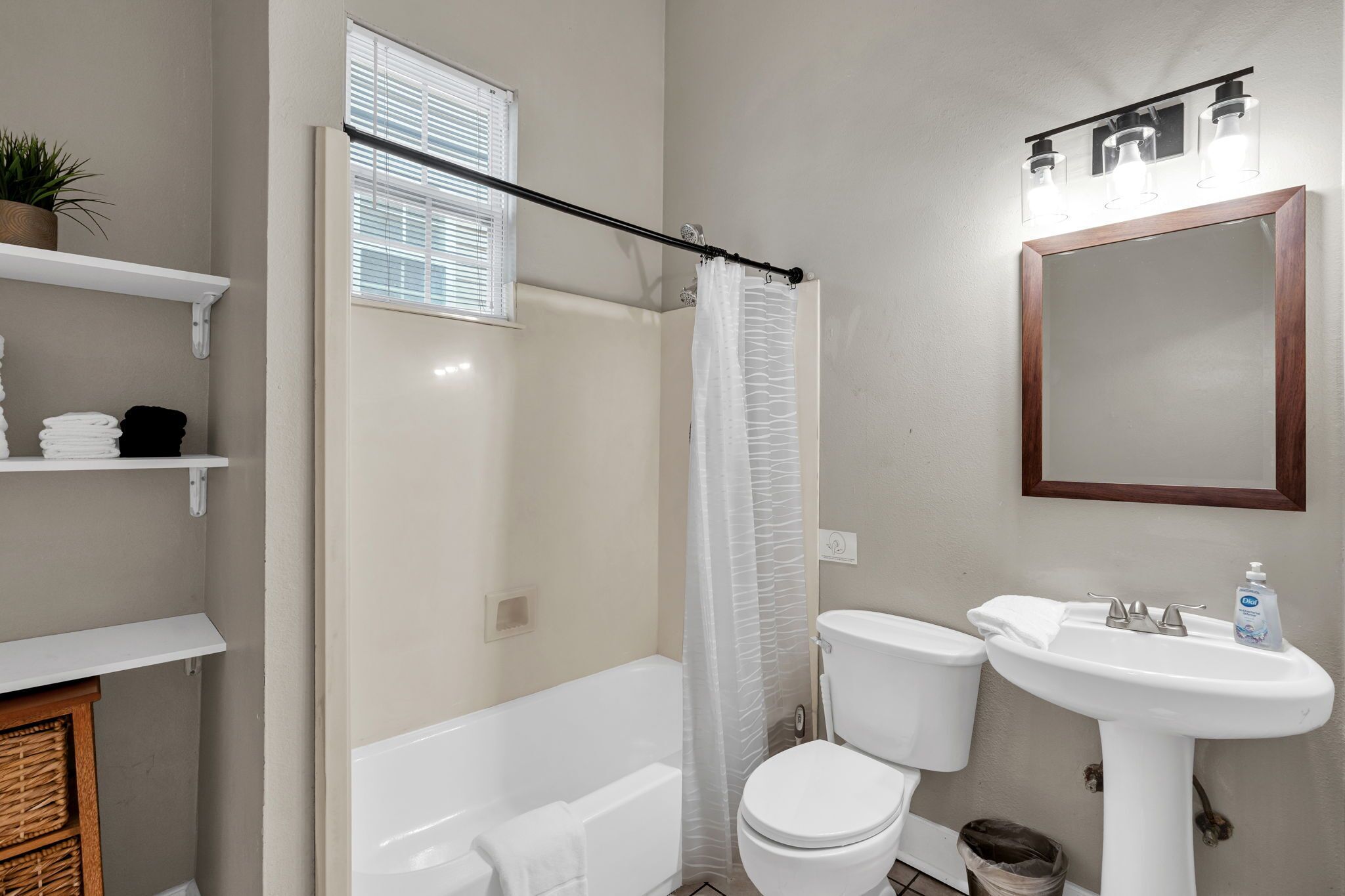 Un baño con bañera, inodoro, lavamanos y cortina de ducha.