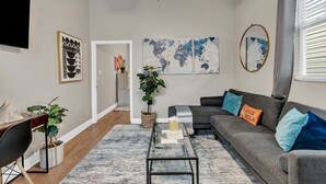 Un salon moderne avec un canapé gris, une table basse et un téléviseur fixé au mur.
