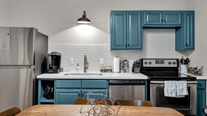 Une cuisine moderne avec des armoires de couleur turquoise, un réfrigérateur en acier inoxydable, une machine à café et un lave-vaisselle.