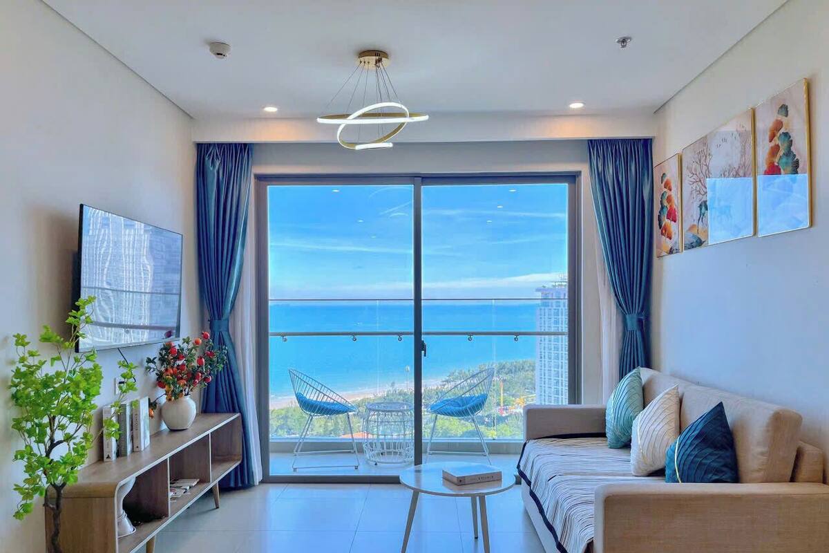 Ein modernes Wohnzimmer mit einem großen Schiebeglasfenster, das auf einen Balkon mit Blick auf die Stadt führt.