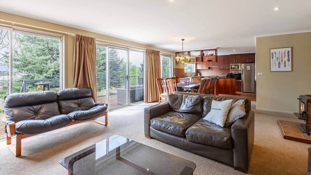 Ein geräumiges Wohnzimmer mit einer Ledersofa, einem Glastisch und einem Essbereich mit Holzsesseln und einem Tisch.