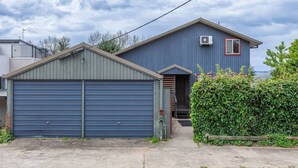 Ein eingeschossiges Gebäude mit blauer Fassade, einer Garage mit heruntergelassener Rolltreppe und einem kleinen Eingang mit Stufen.