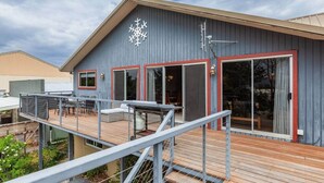 Ein modernes Haus mit Terrasse, großen Schiebeglastüren und einem Metallgeländer.