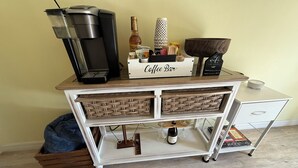 A coffee bar setup with a coffee maker, a bottle, and a sign that reads "Coffee Bar".