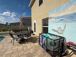 Une terrasse avec une table et des chaises, un parasol et une piscine.
