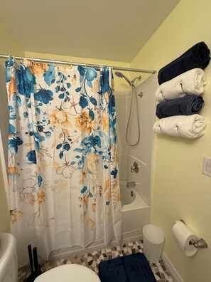 Une salle de bain équipée d’une douche, de toilettes et d’un porte-serviettes avec des serviettes.