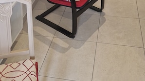Une chaise rouge dans une pièce aux murs blancs, une petite table avec un livre et un élément décoratif mural.