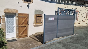 Un bâtiment doté d’une porte en bois, d’un mur en pierre et d’un portail en métal.