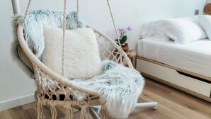 A room with a macrame hanging chair, a bed with white bedding, and a small potted plant on a nightstand. - Il Nido tra le Mura (Como)