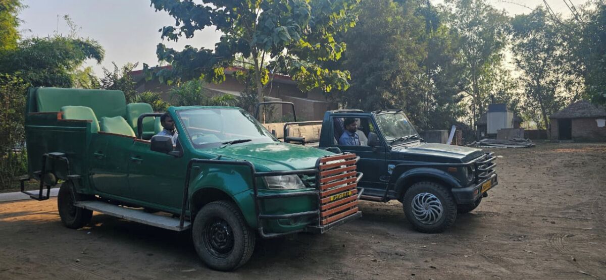 Uma caminhonete verde com um reboque plataforma e uma caminhonete preta estacionadas em uma estrada de terra.