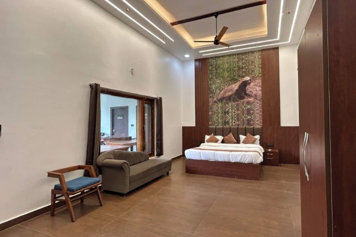 A modern bedroom with a large bed, a seating area, and a wardrobe.