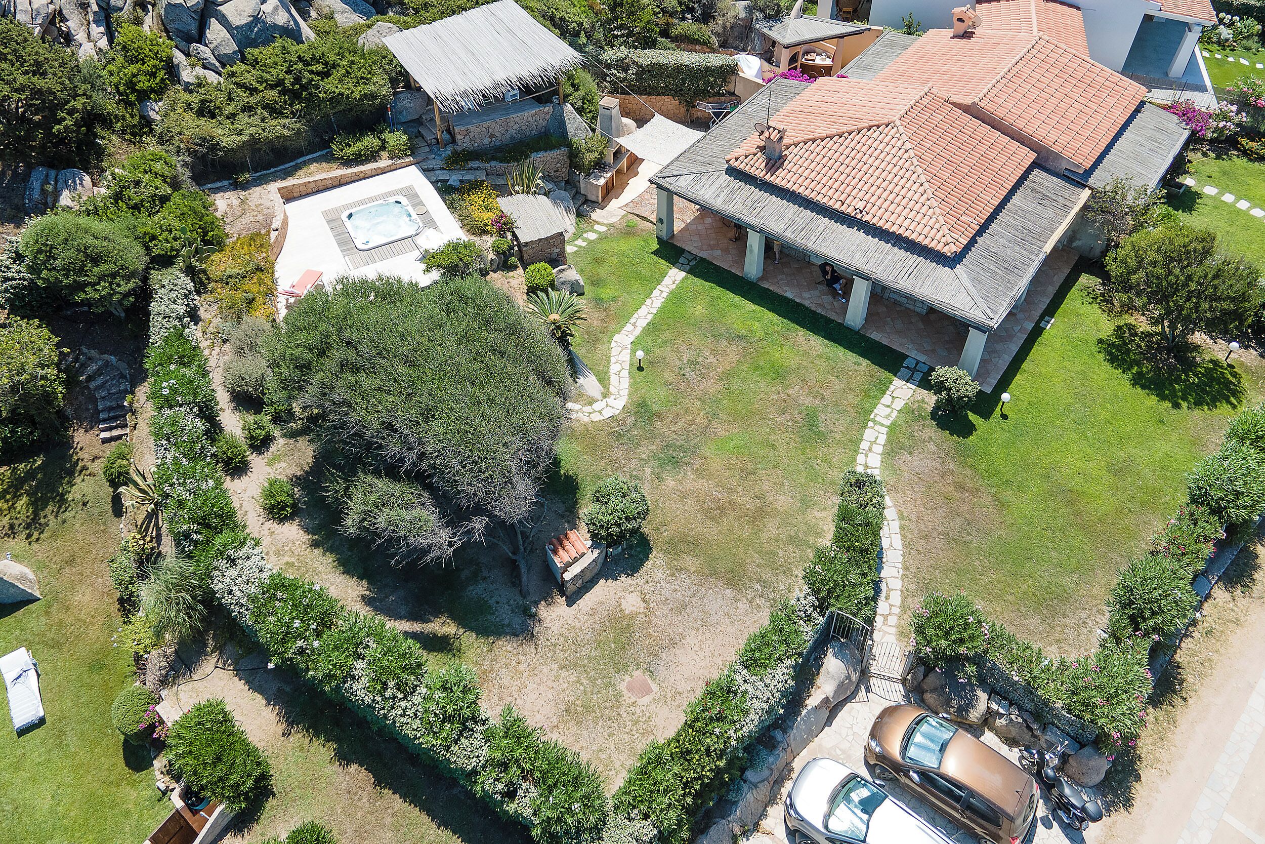 An aerial view of a property with a large house, a swimming pool, and surrounding greenery.