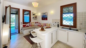 Una cocina moderna con una isla central, muebles blancos y un amplio ventanal con vistas.
