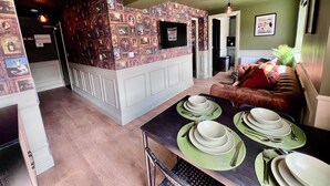 A dining area with a table set for four, a sofa, and a wall with a patterned wallpaper. - Large Period Property On The Edge Of City Centre. (Worcester)