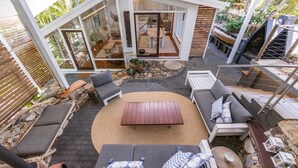 Eine moderne Außenpatio mit einem zentralen Holztisch, umgeben von Sitzbereichen und einem Steinweg.
