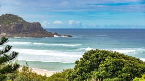 Eine Küstenlandschaft mit felsigen Klippen, einem Sandstrand und dichter Vegetation.