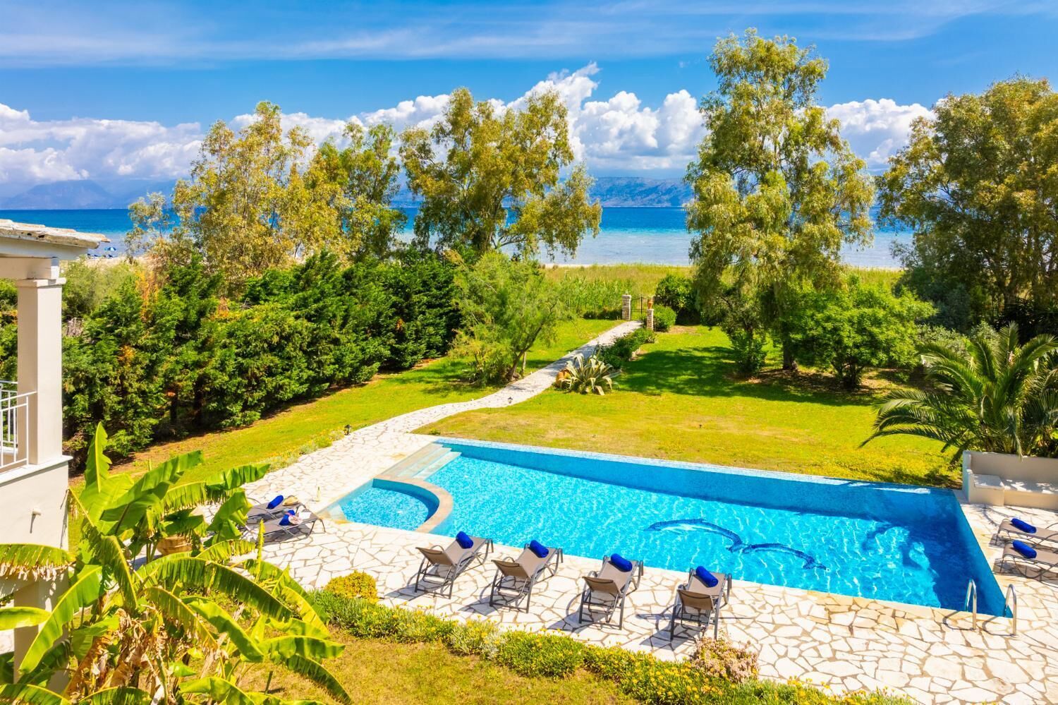 A swimming pool with lounge chairs and a view of the sea.
