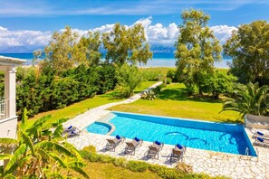 A swimming pool with lounge chairs and a view of the sea. - Ormos Beach House in Apraos (Corfu)