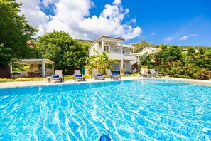 A swimming pool with lounge chairs and a building with a balcony in the background. - Ormos Beach House in Apraos (Corfu)
