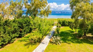 A pathway leading to a body of water, surrounded by lush greenery and trees. - Ormos Beach House in Apraos (Corfu)