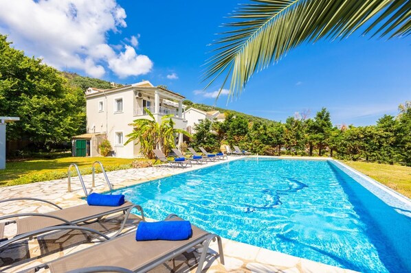 A swimming pool with lounge chairs and a building in the background. - Ormos Beach House in Apraos (Corfu)