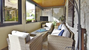A cozy room with wicker furniture, a flat-screen TV, and a large window overlooking a garden. - Holiday Home With Garden and BBQ in Umag (Umag)