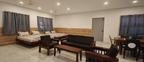 A spacious living room with a sofa set, a dining table, and a ceiling fan.