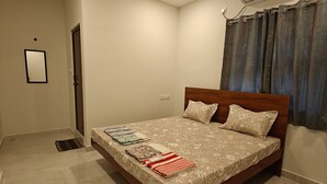 A bedroom with a bed, a ceiling fan, an air conditioning unit, and a window with curtains. - Hotel Mauris & Restaurant By Wishotel  (Indore)