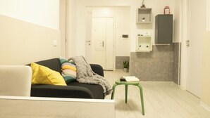 Ein modernes Wohnzimmer mit einer Couch, einem kleinen Tisch und einer Tür zu einer Küchenzeile.
