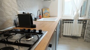 Eine moderne Küche mit einem Gasherd, einer Kaffeemaschine und einem Schild mit der Aufschrift 'Plum and Juice Hot Dogs'.