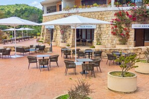 An outdoor patio area with stone walls, wicker furniture, and umbrellas.