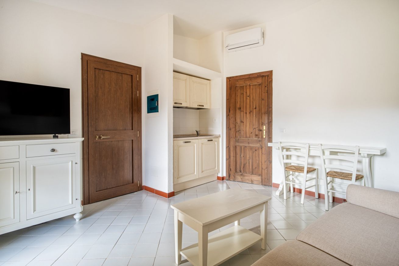 Un espacio habitable compacto con kitchenette, un televisor de pantalla plana, una mesa de comedor y un sofá.