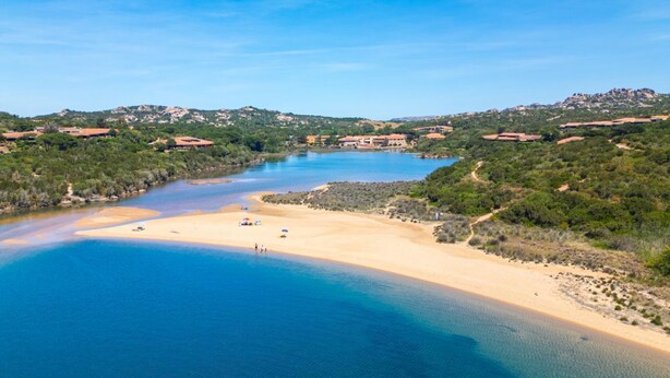 A coastal landscape with a sandy beach, clear blue water, and surrounding greenery. - A sophisticated space designed to accommodate up to four people, where comfort and style meet. The living room features a comfortable double sofa bed, while the bedroom, equipped with a double bed, offers an intimate and relaxing atmosphere. The modern b (Costa Serena)