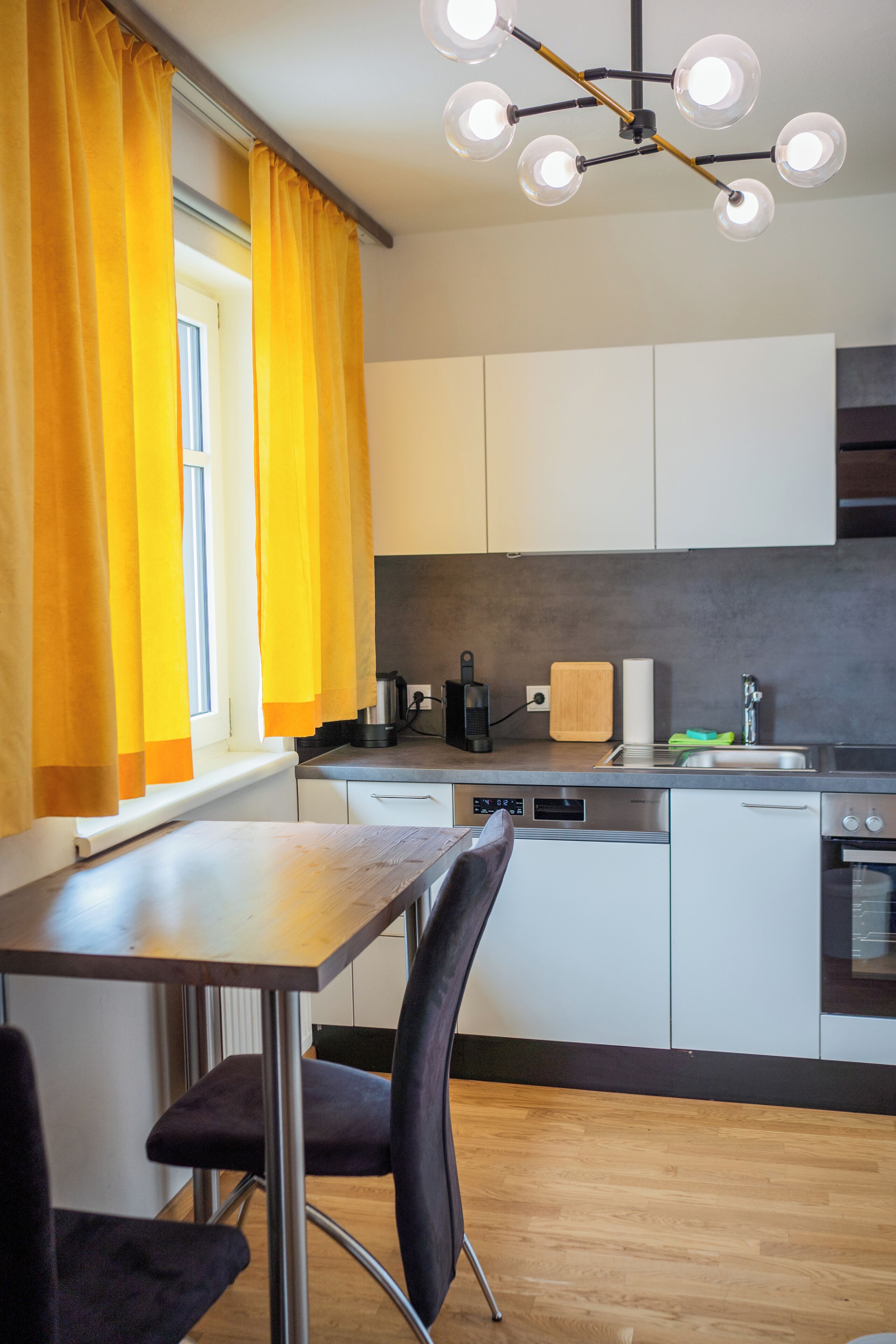 Una cocina moderna con comedor, que presenta una mesa de madera, sillas y un horno empotrado.