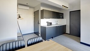 A modern kitchen with grey cabinets, a microwave, and a sink. There is a dining area with a wooden table and two chairs. - Superb Family Apartment - 1 Bedroom (Paris)
