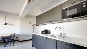A modern kitchen with grey cabinets, a stainless steel sink, and a Bosch microwave. - Superb Family Apartment - 1 Bedroom (Paris)