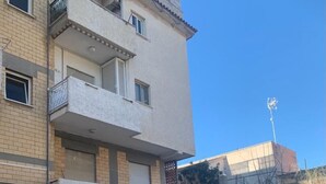 Ein mehrstöckiges Gebäude mit Balkonen, einem gut sichtbaren Eingang und blauem Himmel.