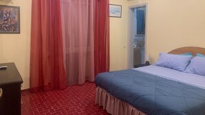 Ein Schlafzimmer mit Bett, Kommode, Heizkörper und einem Fenster mit Vorhängen.