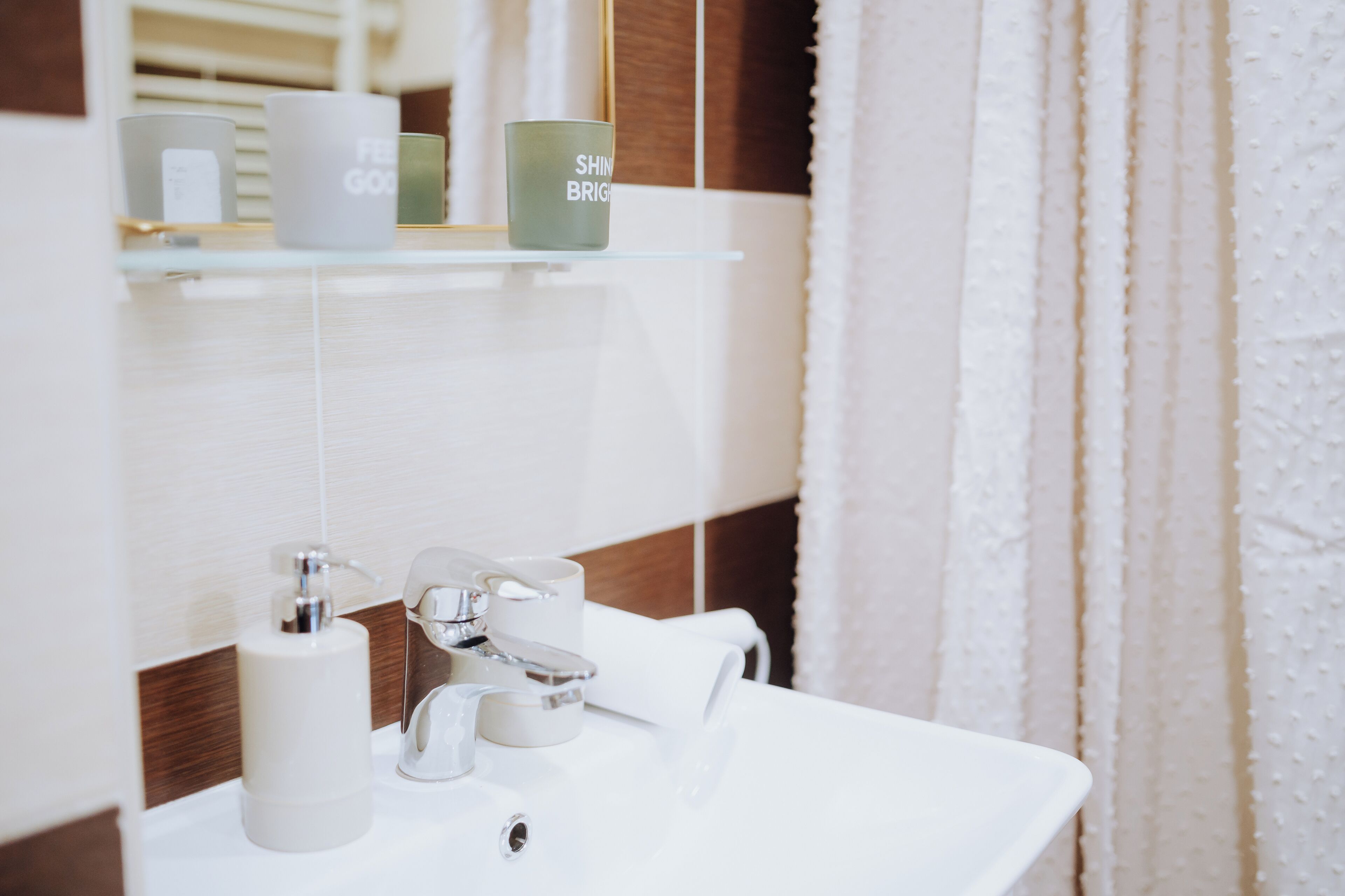 A bathroom with a white sink, a mirror, and a shelf with toiletries.